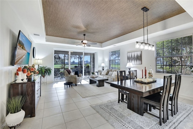 dining space featuring a tray ceiling, light tile patterned floors, and ceiling fan