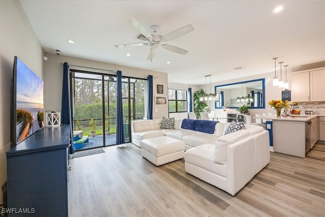 living room featuring ceiling fan with notable chandelier and light hardwood / wood-style floors