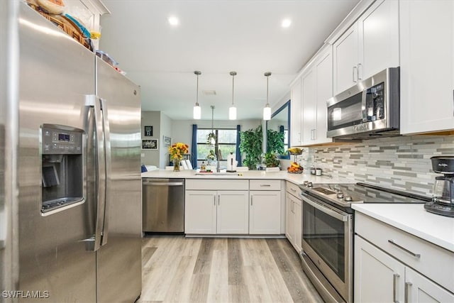 kitchen featuring white cabinets, hanging light fixtures, light hardwood / wood-style floors, and stainless steel appliances