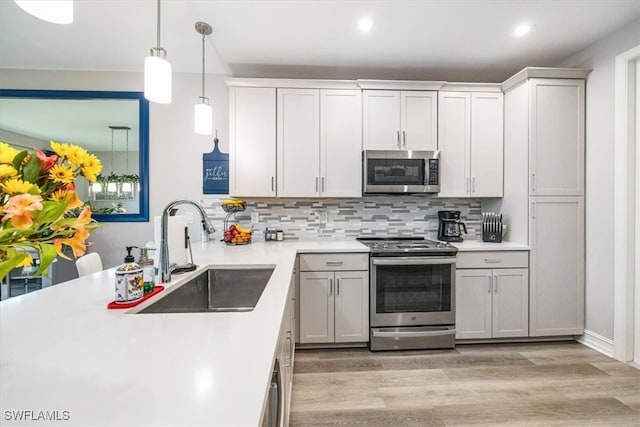 kitchen featuring light hardwood / wood-style floors, appliances with stainless steel finishes, sink, and tasteful backsplash