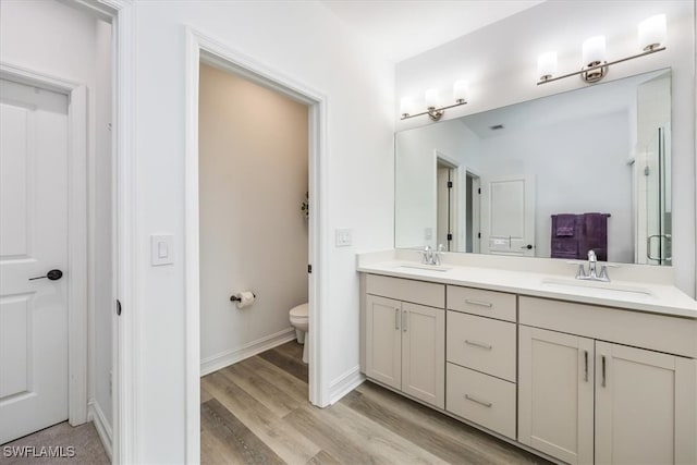 bathroom featuring an enclosed shower, vanity, hardwood / wood-style flooring, and toilet