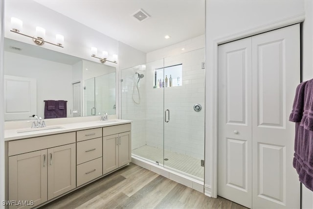 bathroom with hardwood / wood-style flooring, vanity, and walk in shower