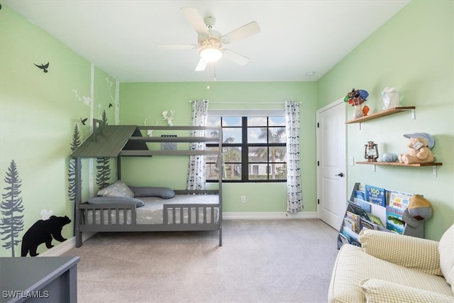 carpeted bedroom with a crib and ceiling fan