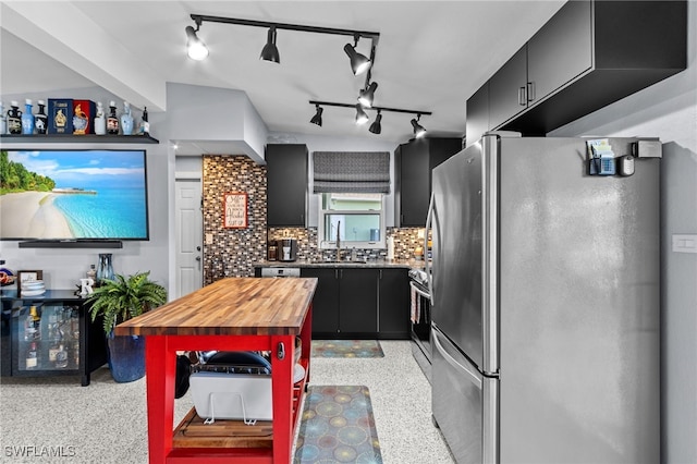 kitchen featuring sink, backsplash, appliances with stainless steel finishes, and track lighting