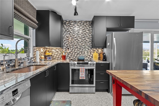 kitchen featuring decorative backsplash, appliances with stainless steel finishes, wood counters, and sink