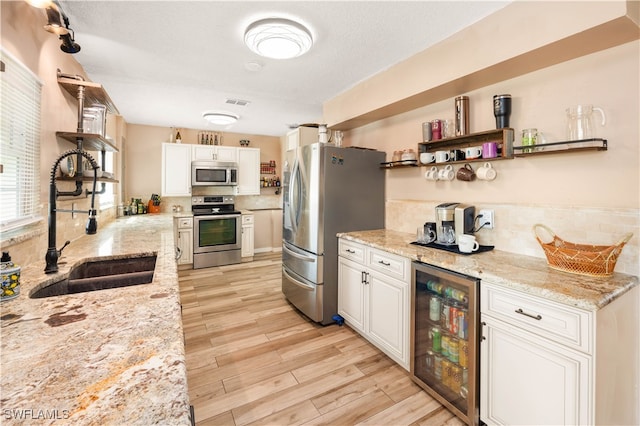 kitchen with light stone countertops, sink, white cabinetry, stainless steel appliances, and wine cooler