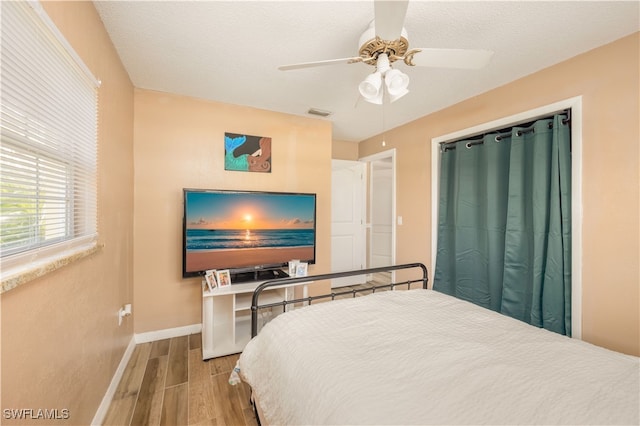 bedroom with a textured ceiling, hardwood / wood-style flooring, and ceiling fan