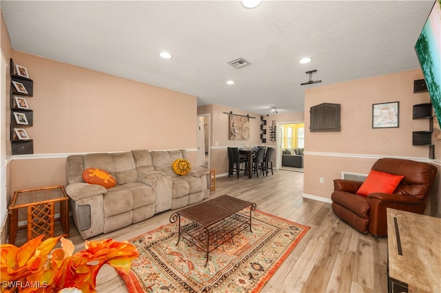 living room with a textured ceiling and light hardwood / wood-style flooring