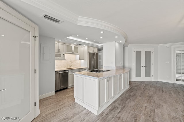 kitchen with stainless steel appliances, white cabinetry, light wood-type flooring, and crown molding