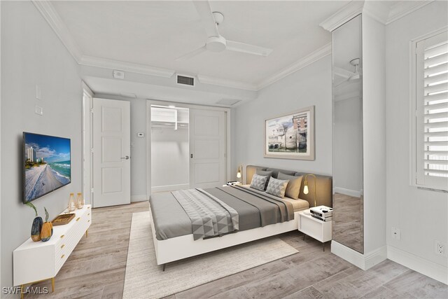 bedroom with a closet, a spacious closet, ornamental molding, light hardwood / wood-style floors, and ceiling fan