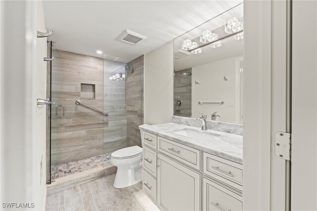 bathroom featuring toilet, an enclosed shower, and vanity