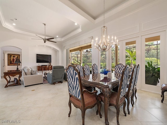 tiled dining space featuring a raised ceiling, ornamental molding, and ceiling fan with notable chandelier