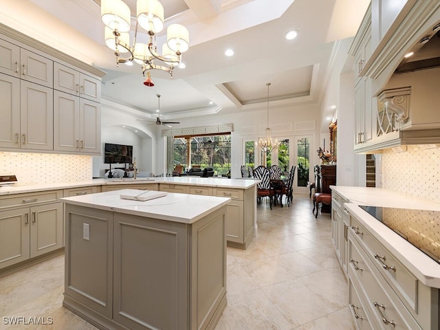 kitchen with crown molding, hanging light fixtures, kitchen peninsula, a kitchen island, and ceiling fan with notable chandelier