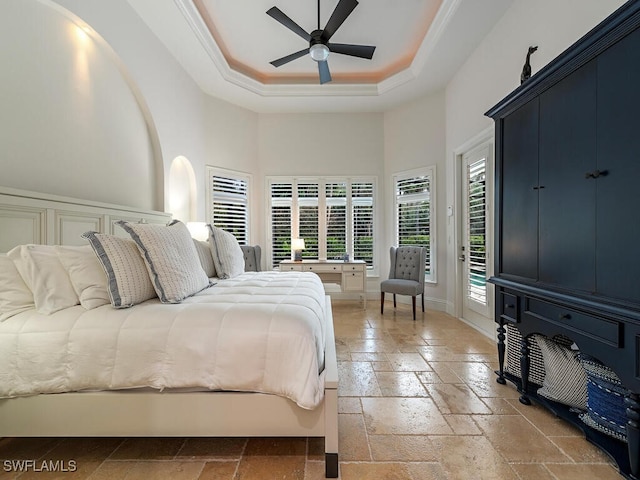 bedroom with a towering ceiling, ornamental molding, access to outside, ceiling fan, and a tray ceiling