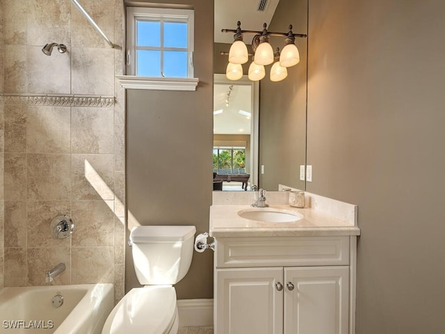 full bathroom featuring vanity, tiled shower / bath combo, and toilet