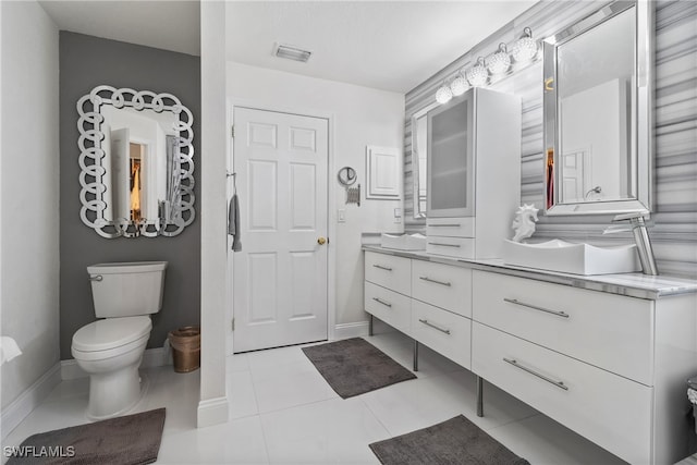 bathroom with toilet, vanity, and tile patterned floors