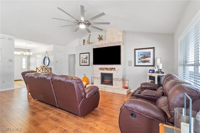 living room featuring a fireplace, ceiling fan with notable chandelier, wood-type flooring, and vaulted ceiling