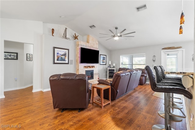 living room with dark wood-type flooring, ceiling fan, a fireplace, and lofted ceiling