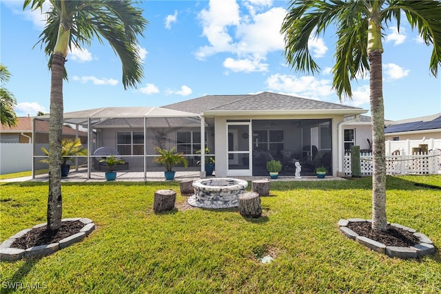 back of property with an outdoor fire pit, a sunroom, glass enclosure, a patio, and a lawn