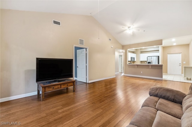 living room with ceiling fan, hardwood / wood-style flooring, and lofted ceiling