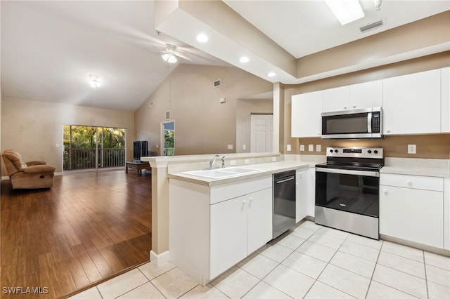 kitchen with white cabinets, stainless steel appliances, sink, kitchen peninsula, and light tile patterned floors