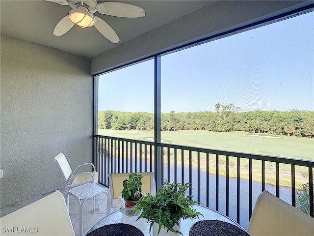 sunroom / solarium featuring a water view and ceiling fan