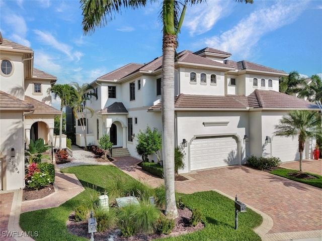 27588 River Reach Dr, Bonita Springs, FL 34134 - mediterranean / spanish-style house with decorative driveway, stucco siding, an attached garage, and a tile roof