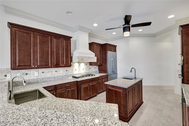 kitchen featuring custom range hood, stainless steel appliances, sink, and light stone counters