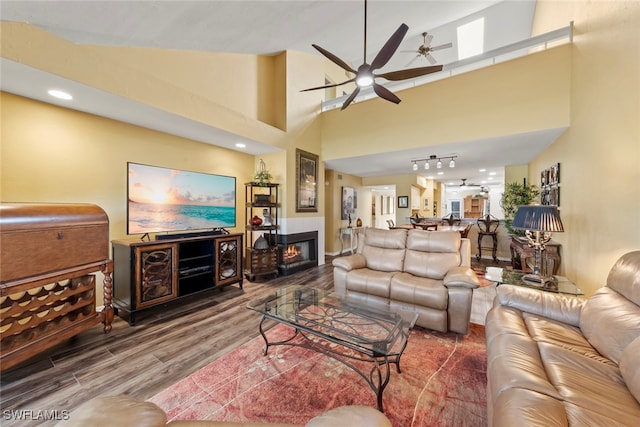 living room featuring a towering ceiling, hardwood / wood-style flooring, and ceiling fan