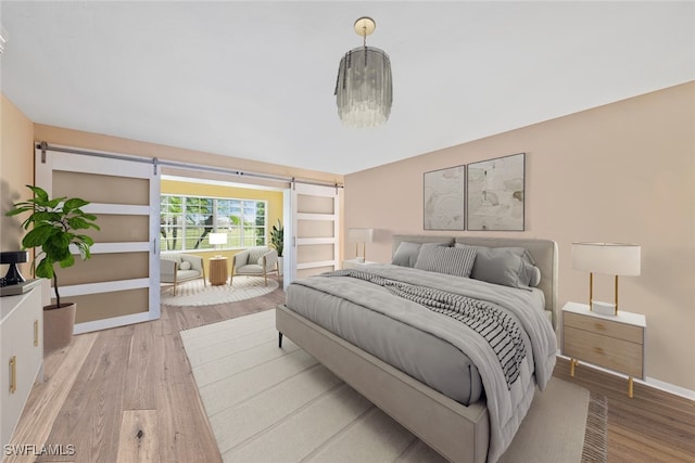 bedroom featuring a barn door and light hardwood / wood-style floors