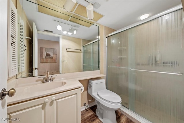 bathroom featuring wood-type flooring, vanity, toilet, and a shower with shower door