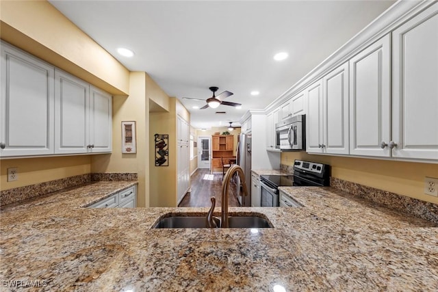 kitchen featuring light stone countertops, stainless steel appliances, ceiling fan, sink, and white cabinetry