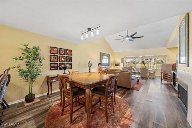 dining space with ceiling fan, lofted ceiling, and dark wood-type flooring