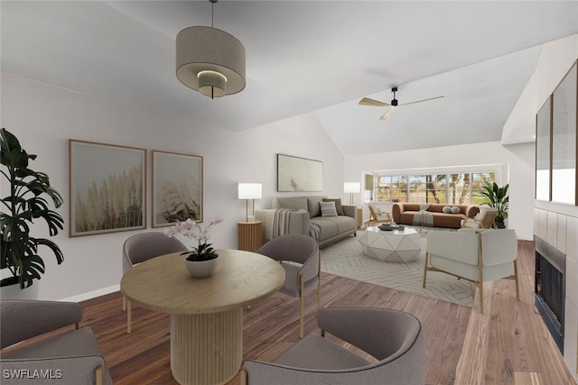 dining area featuring a tile fireplace, ceiling fan, hardwood / wood-style floors, and lofted ceiling