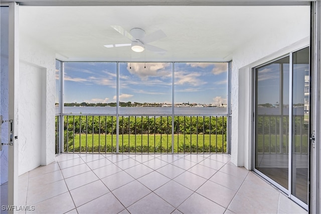 unfurnished sunroom with ceiling fan and a water view