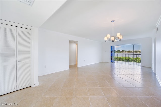 spare room featuring ornamental molding, light tile patterned floors, and an inviting chandelier