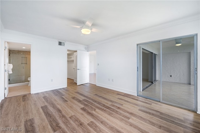 unfurnished bedroom with light wood-type flooring, a closet, ensuite bath, and ceiling fan