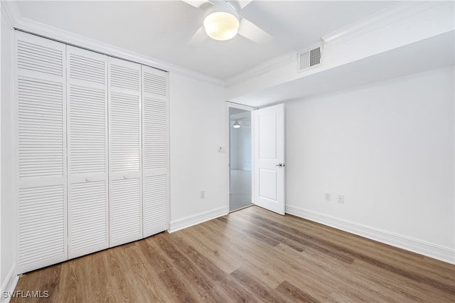 unfurnished bedroom featuring light hardwood / wood-style flooring, a closet, crown molding, and ceiling fan