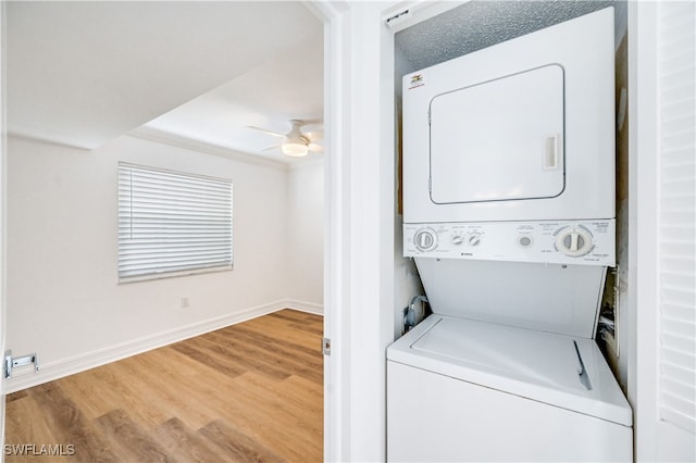 clothes washing area featuring ceiling fan, wood-type flooring, stacked washing maching and dryer, and ornamental molding