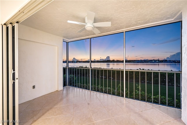 unfurnished sunroom featuring ceiling fan and a water view