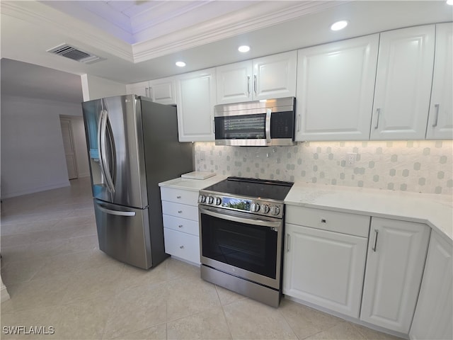 kitchen featuring white cabinets, appliances with stainless steel finishes, decorative backsplash, and ornamental molding