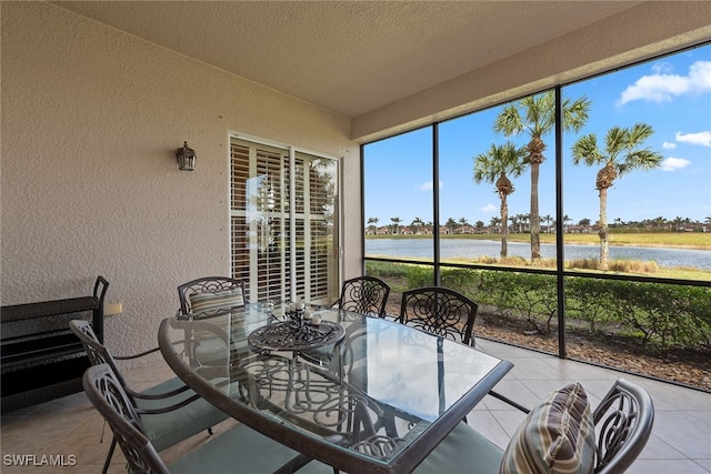 sunroom featuring a water view