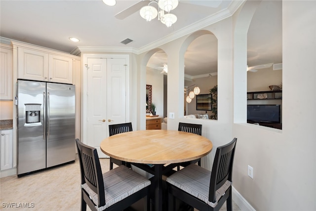 tiled dining space with ceiling fan and crown molding