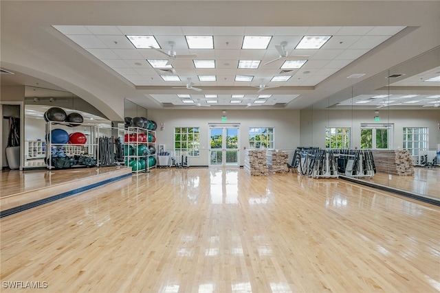 exercise room with a paneled ceiling, wood-type flooring, and french doors