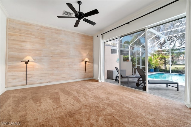 spare room with carpet floors, wood walls, and crown molding