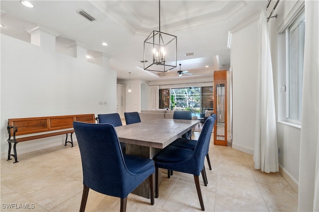 dining area with a tray ceiling, light tile patterned floors, ornamental molding, and ceiling fan with notable chandelier