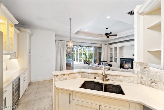 kitchen featuring sink, ceiling fan, beverage cooler, a raised ceiling, and pendant lighting