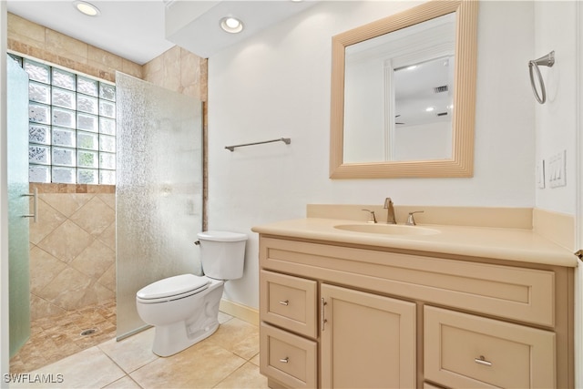 bathroom featuring tiled shower, vanity, tile patterned floors, and toilet