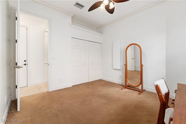 unfurnished bedroom featuring a closet, light colored carpet, ceiling fan, and crown molding