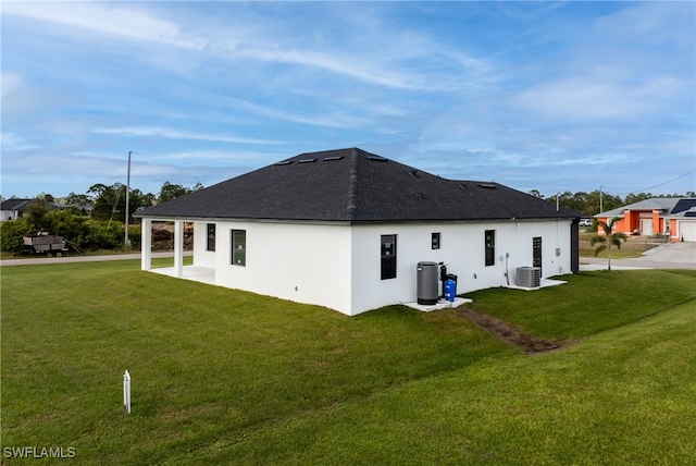 rear view of house featuring a yard and central air condition unit